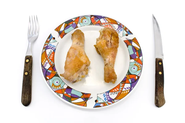 Жареные куриные ножки на тарелке с вилкой и ножом — стоковое фото