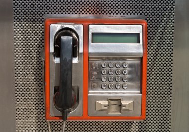 Orange public telephone on metallic background clipart