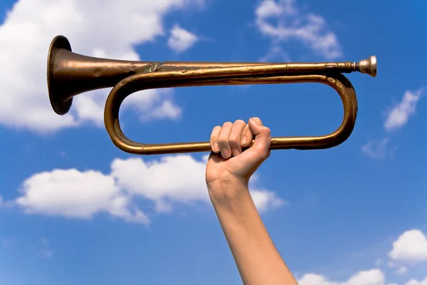 Old army trumpet in hand over blue sky — Stock Photo, Image