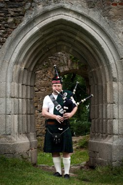 Bagpiper under an medieval Archway clipart