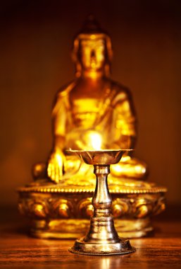 Golden Buddha with oil lamp clipart