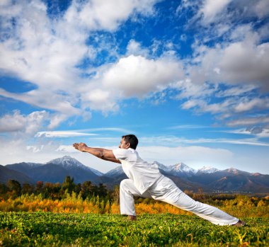 Yoga warrior pose in mountains clipart