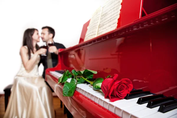 Rode roos op piano — Stockfoto