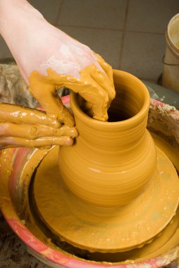 Hands of a potter, creating an earthen jar of white clay clipart