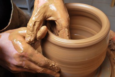 Hands of a potter, creating an earthen jar on the circle clipart