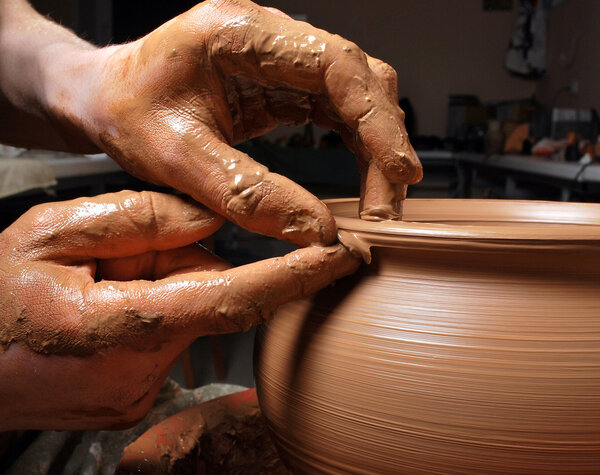 Hands of a potter, creating an earthen jar on the circle