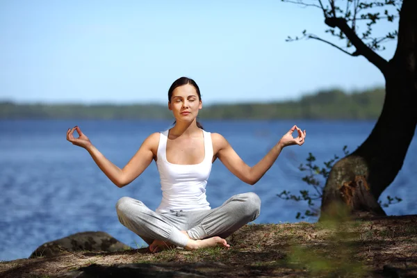 Schönes junges Mädchen trainiert Yoga in der Nähe eines Sees — Stockfoto