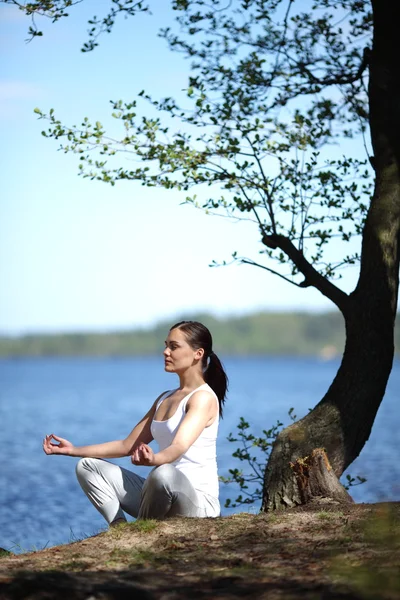 Bela menina formação ioga perto de um lago — Fotografia de Stock