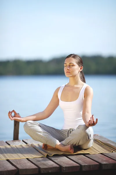 Bella ragazza formazione yoga vicino a un lago — Foto Stock