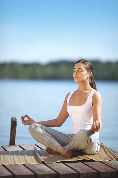 Schönes junges Mädchen trainiert Yoga in der Nähe eines Sees — Stockfoto