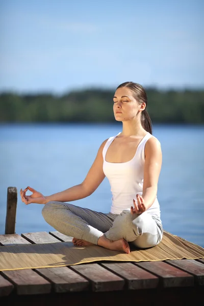 Bella ragazza formazione yoga vicino a un lago — Foto Stock