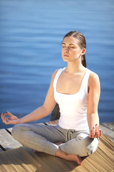 Güzel genç kız eğitim yoga bir göl yakınında — Stok fotoğraf