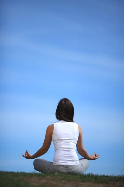 Красивая молодая девушка тренирует йогу на солнечном лугу — стоковое фото