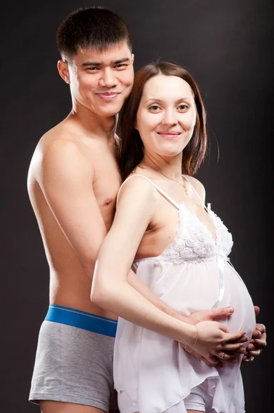 若い幸せ妊娠カップル愛スタジオに黒い背景へのクローズ アップ — ストック写真
