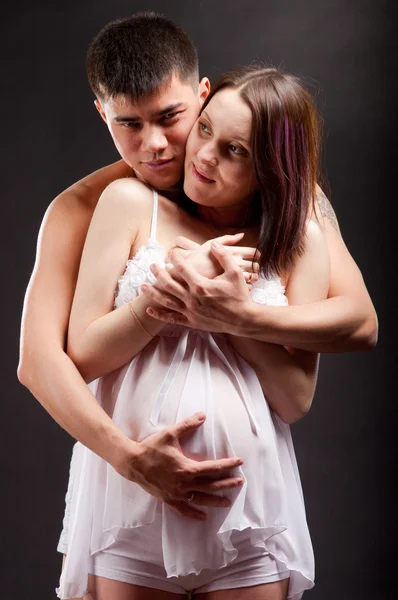 Unga lyckliga gravida par i älskar närbild på svart bakgrund i studio — Stockfoto