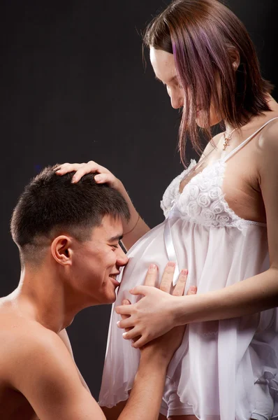 Unga lyckliga gravida par i älskar närbild på svart bakgrund i studio Stockfoto