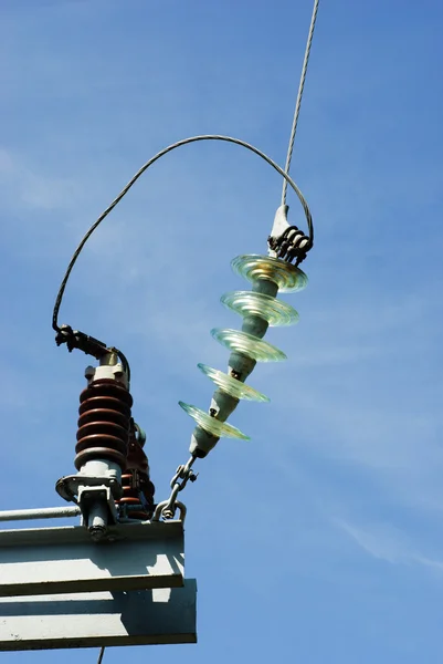 Isoladores em um pilar elétrico de alta tensão jn o fundo do céu azul — Fotografia de Stock
