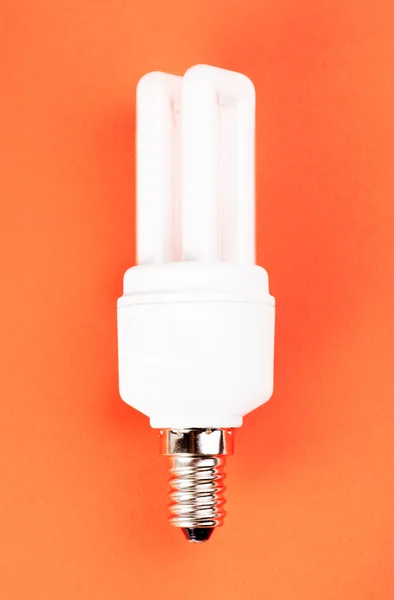 stock image Energy saving light bulb on red background