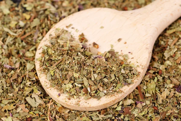Pile of ground dried Basil (Sweet Basil) as background with wooden spoon. Used as a spice in culinary herb all over the world. The plant is also used in medicine. — Stock Photo, Image
