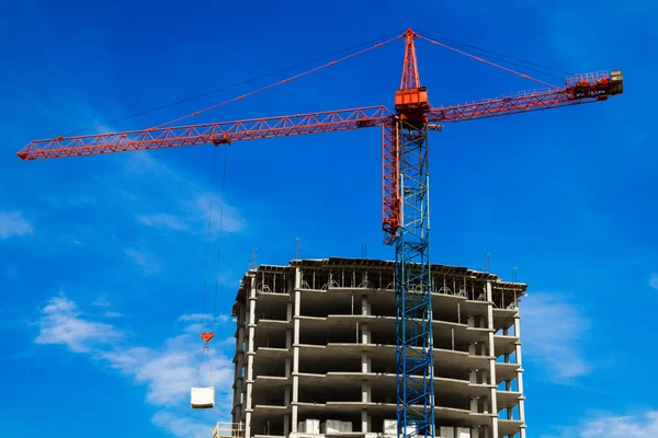 Crane and the house under construction against the blue sky with white clouds in the summer sunny day — Stock Photo, Image