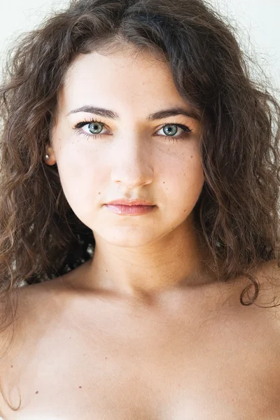 Portret van een mooie jonge brunette met krullend haar — Stockfoto