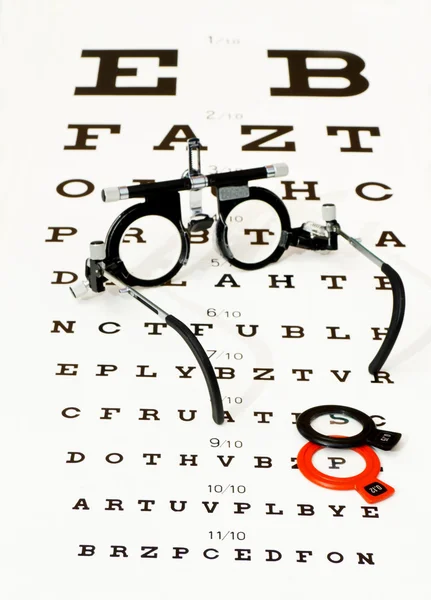 Glasögon liggande på optotype test — Stockfoto