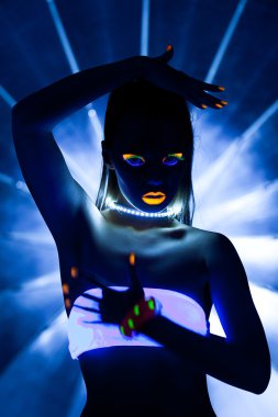 Disco girl with glow make-up dance in uv light