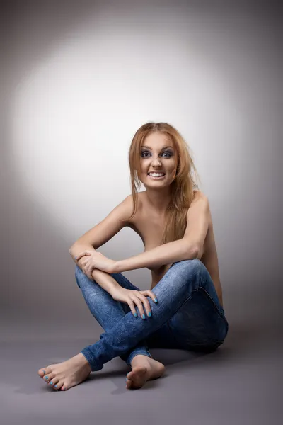 Mezza donna nuda seduta in jeans — Foto Stock