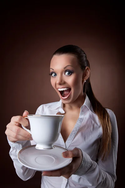 Legrační žena s šálkem kávy úsměv na hnědá — Stock fotografie