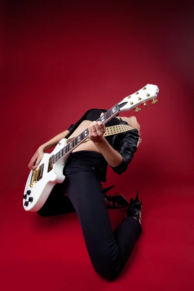 Skalní žena v černé kůži na červené hrát na kytaru — Stock fotografie