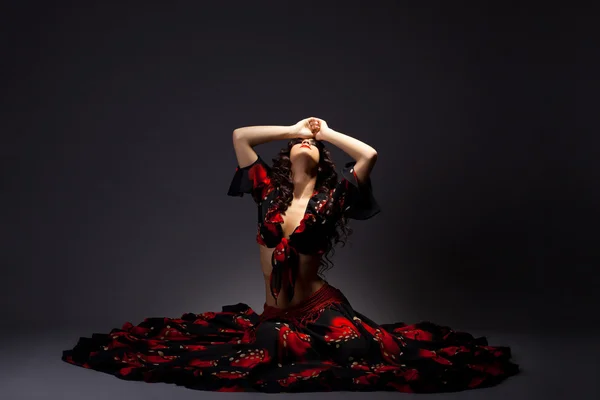 Jovem mulher senta-se em trajes cigano preto e vermelho — Fotografia de Stock