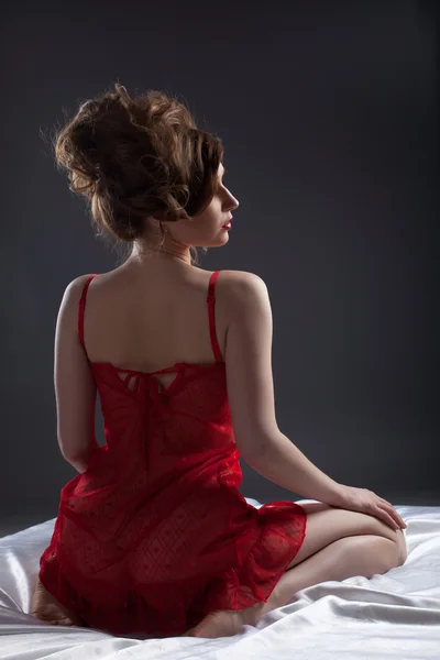 Sexy woman in red portrait on white silk bed — Stock Photo, Image