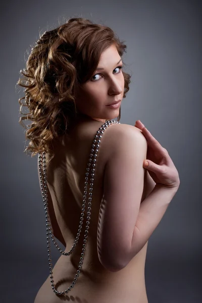 Nude young woman posing with silver beads — Stock Photo, Image