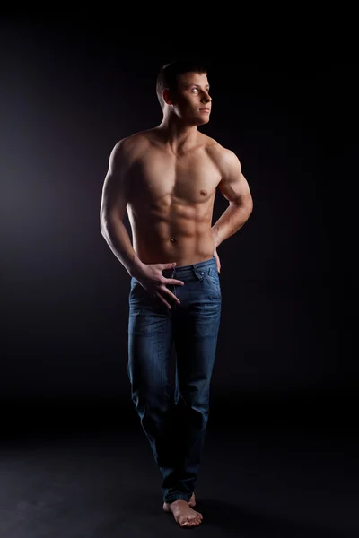 Man with naked torso in jeans posing in dark — Stock Photo, Image