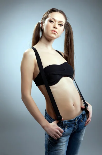 Woman in black bikini and jeans with suspenders — Stock Photo, Image