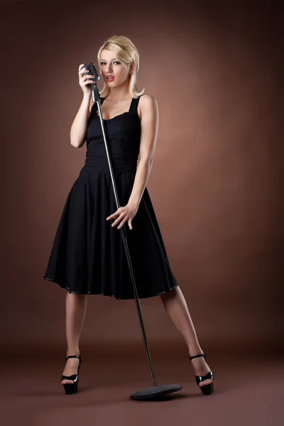 Γυναίκα pin-up κατακόρυφο σε μαύρο χρώμα με μικρόφωνο — Φωτογραφία Αρχείου