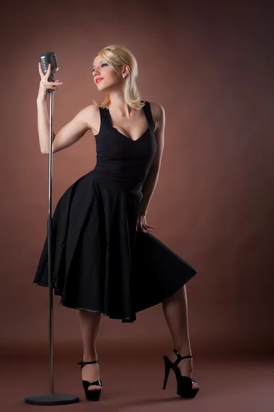 Pin-up-Porträt einer Frau in Schwarz mit Mikrofon — Stockfoto