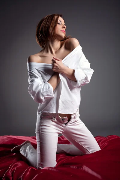 Сексуальная женщина позирует в белой рубашке и джинсах — стоковое фото