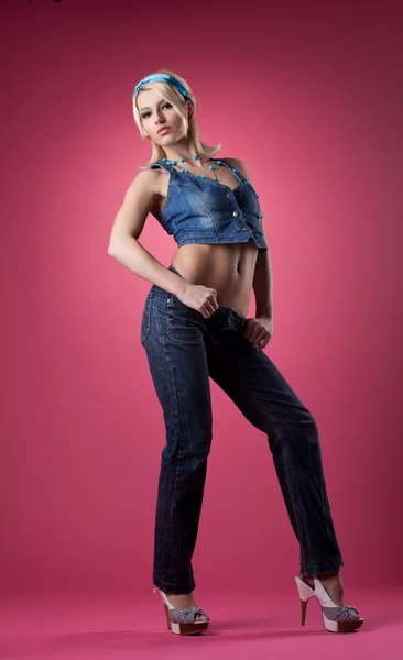 Linda chica sexy posando en jeans sobre fondo rosa —  Fotos de Stock
