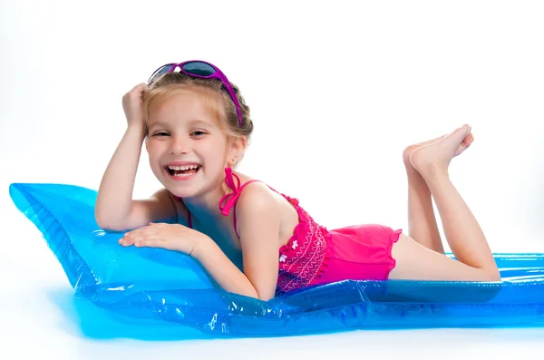Schattig klein meisje in een pak zwemmen op een opblaasbare matras — Stockfoto