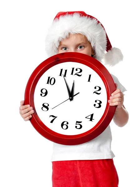 Petite fille mignonne en bonnet de Père Noël avec une horloge — Photo