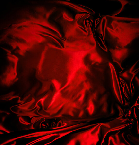 Luxurious red satin fabric with beautiful patterns of folds and shadows showing depth and dimension