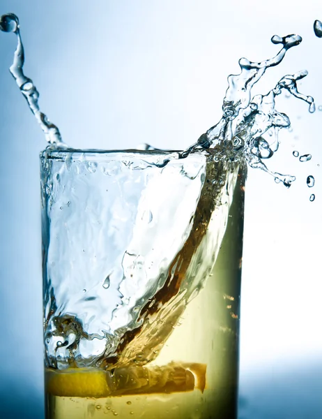 Gocce di limone in un bicchiere di bevanda — Foto Stock