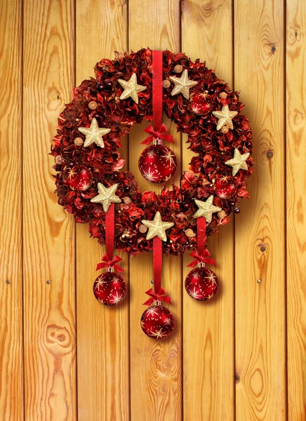 Czerwony wianek Bożego Narodzenia w stare drewniane drzwi — Zdjęcie stockowe