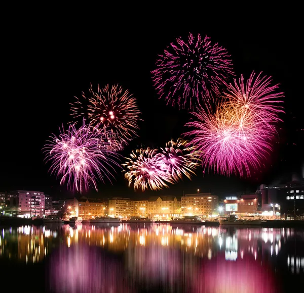 Vuurwerk over stad aan het water — Stockfoto