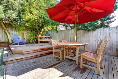 Back yard large deck with red umbrella and chairs. clipart