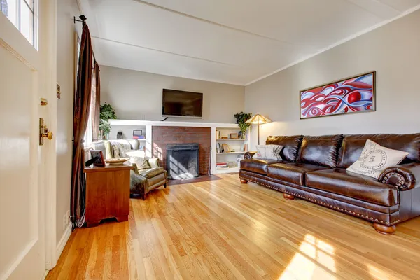 Salón con sofá de cuero, chimenea y TV . — Foto de Stock