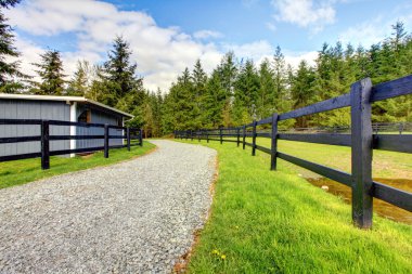 Horse farm with road, fence and shed. clipart