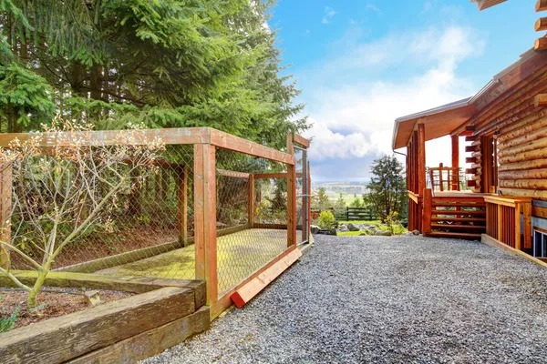 Log cabin with dogs fenced canal area behind the house. — Stock Photo, Image