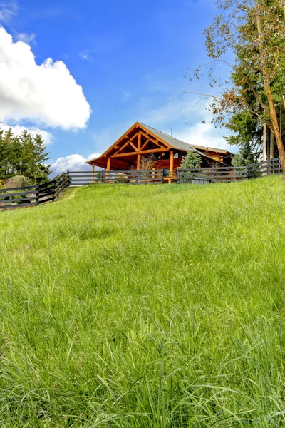 Log cabin on the hill with fresh green grass. — Stock Photo, Image